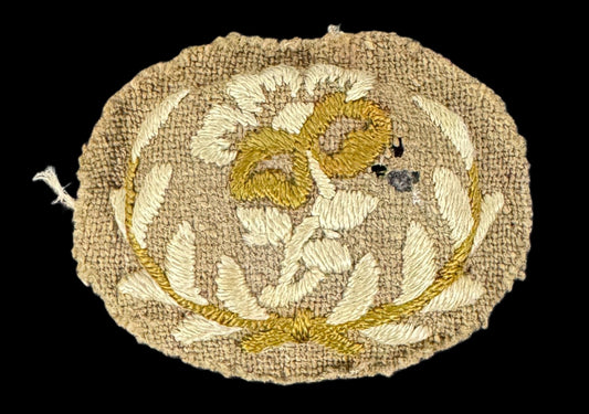 WW1 Queen Mary’s Army Auxiliary Corps Forewoman sleeve badge showing a hand-embroidered rose within a laurel wreath on khaki wool backing.