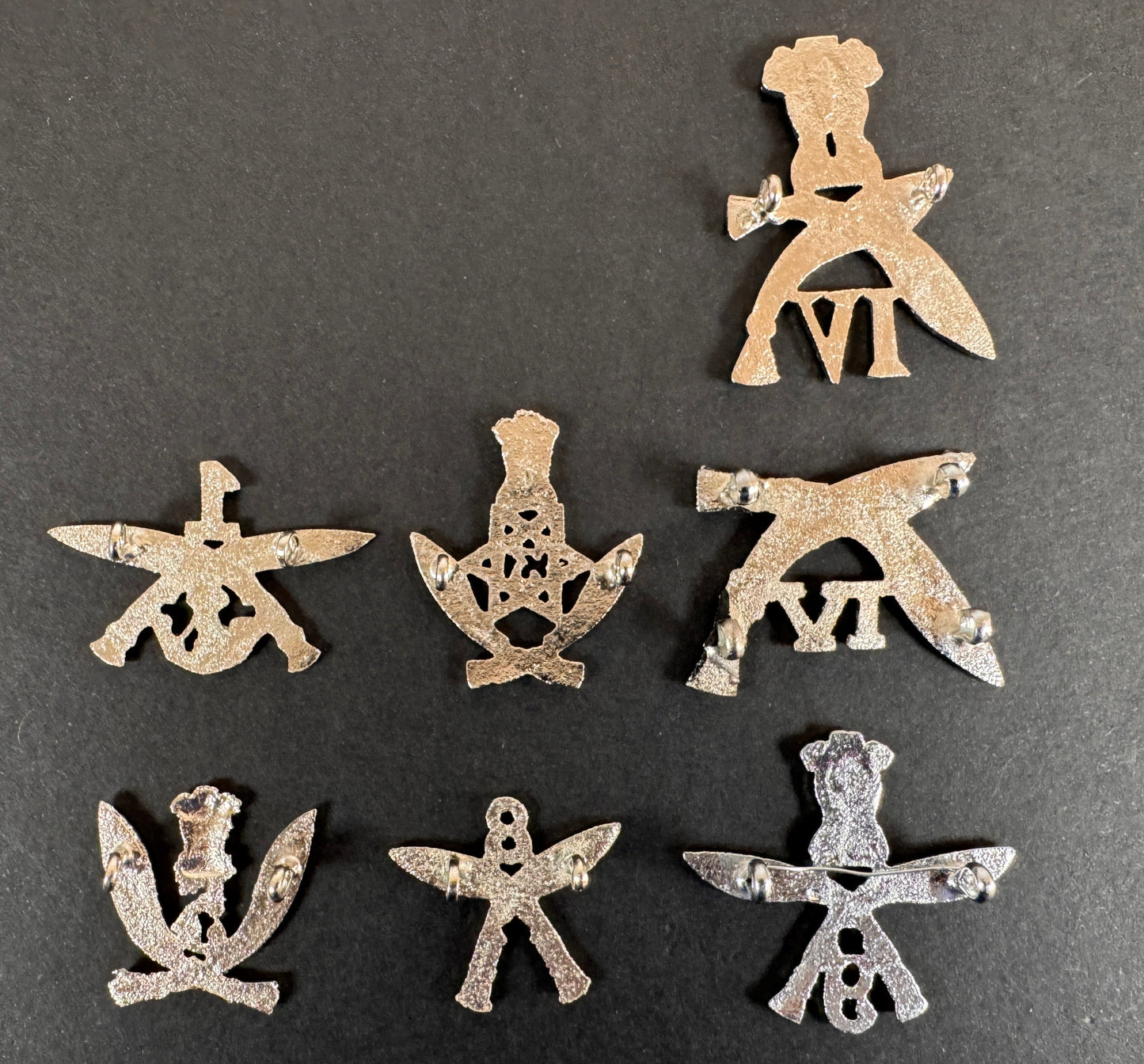 Set of silver gurkha rifles cap badges on a dark gray background