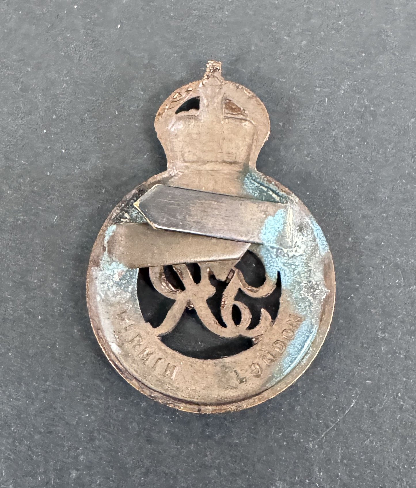 Vintage metal badge with a crown and text on a dark background