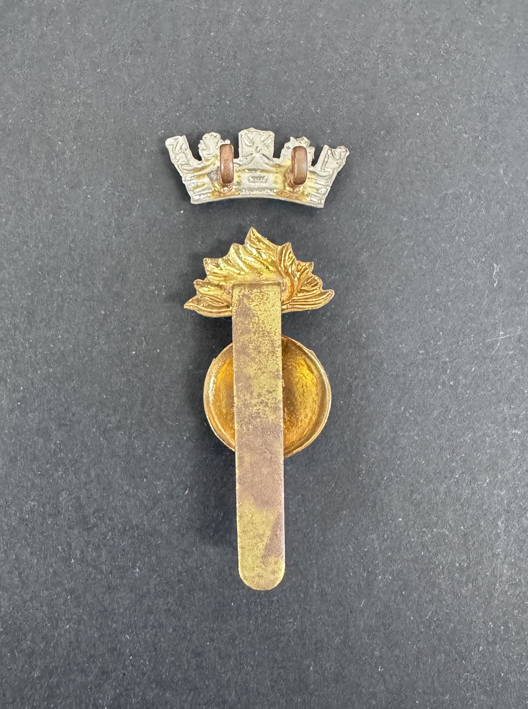 Gold military insignia badge with a crown on a gray background