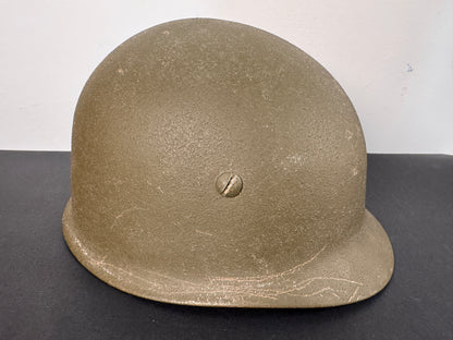 Green military helmet on a black surface with a white background