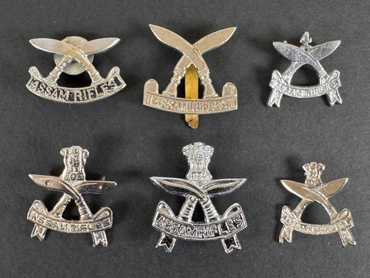 Set of silver gurkha assam rifles military cap badges on a dark background