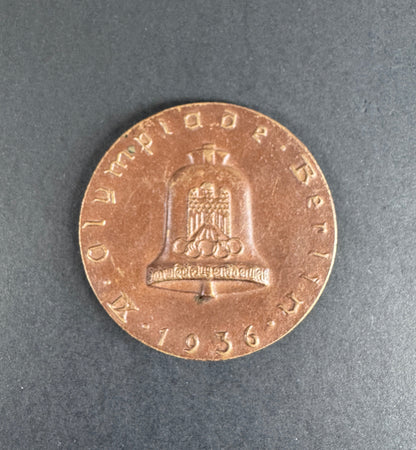Bronze table medal with embossed design on a gray background. For 9th Olympiad Berlin 1936.