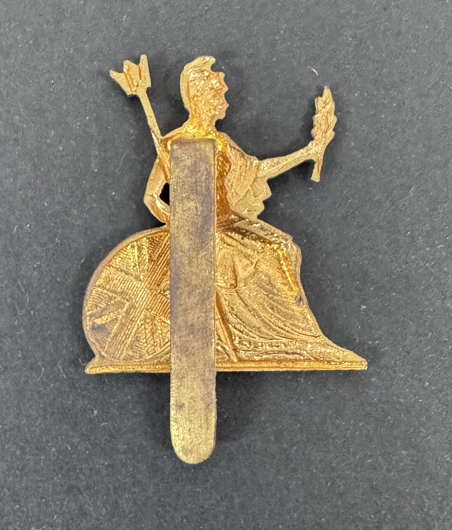 Gold-colored brooch with a seated figure holding an arrow and torch on a dark gray background