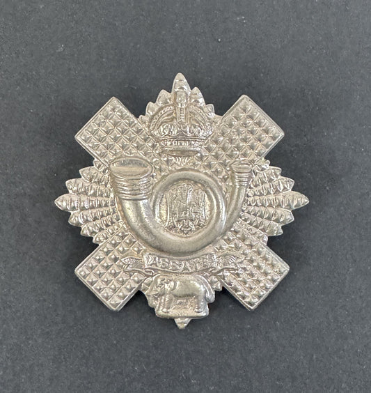 Silver military cap badge on a dark gray background