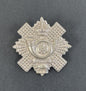 Silver military cap badge on a dark gray background