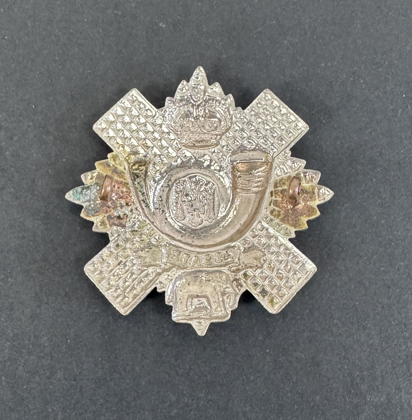 Decorative metal badge with intricate design on a gray background