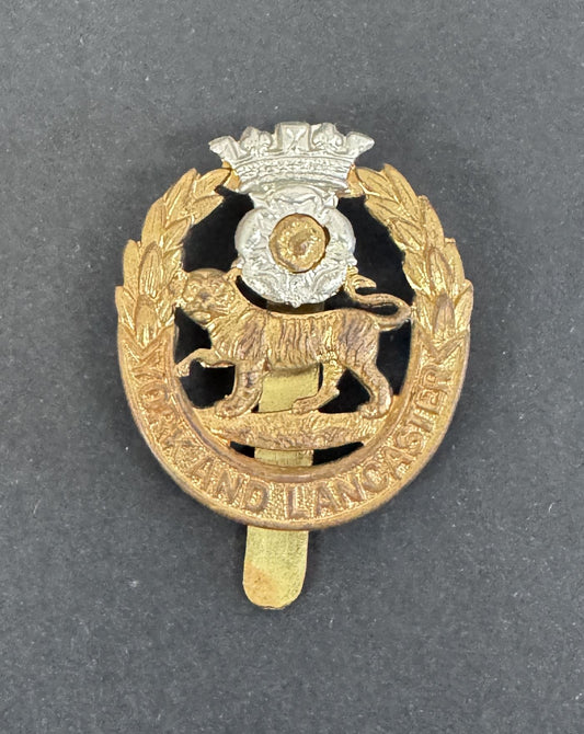 Gold and silver military cap badge with a lion emblem on a gray background