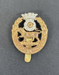 Gold and silver military cap badge with a lion emblem on a gray background