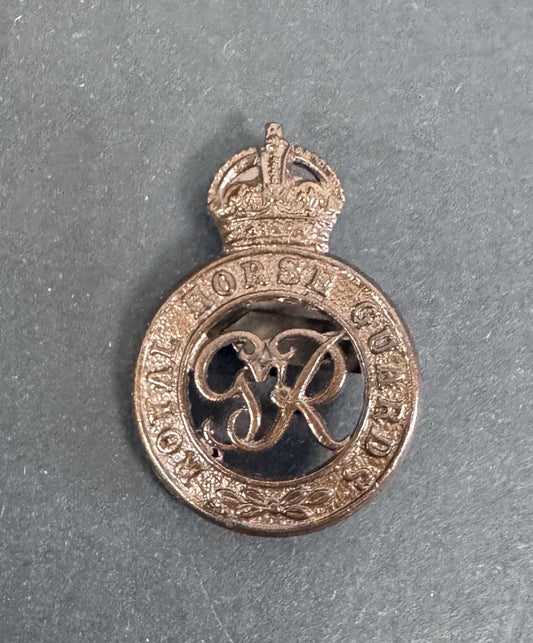 Bronze military badge with crown and letter 'R' on a gray background