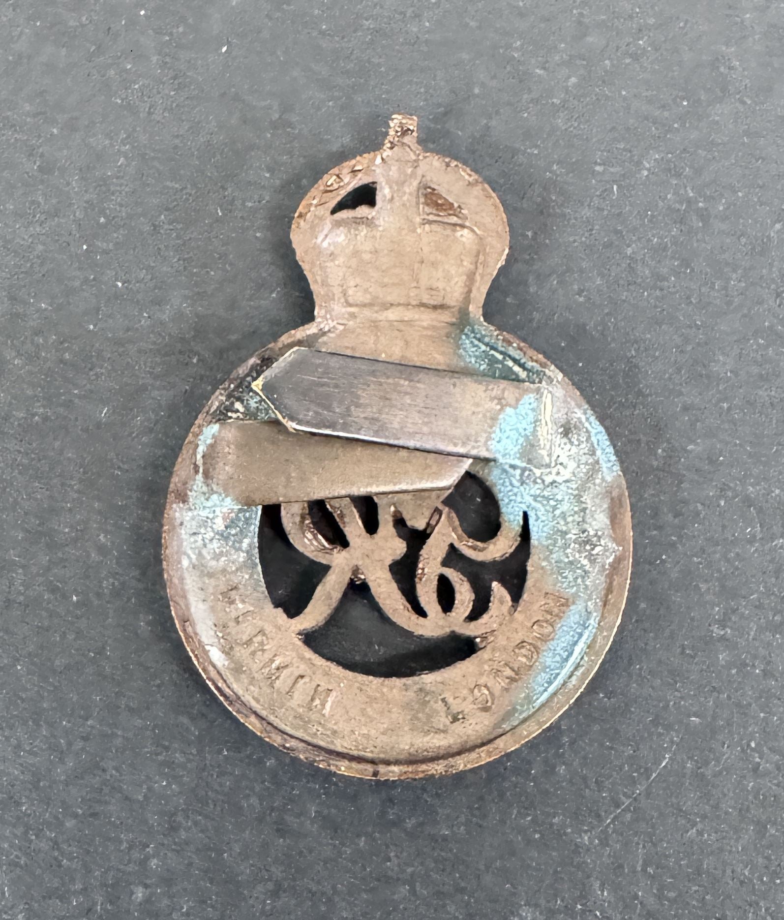 Vintage metal badge with a crown and text on a dark background