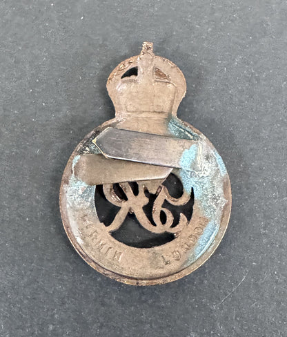 Vintage metal badge with a crown and text on a dark background