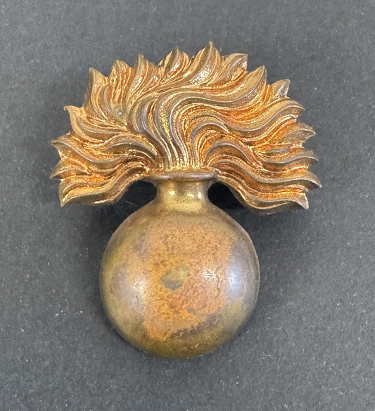 Decorative gold brooch with a spherical base and feather-like top on a dark background