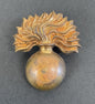 Decorative gold brooch with a spherical base and feather-like top on a dark background