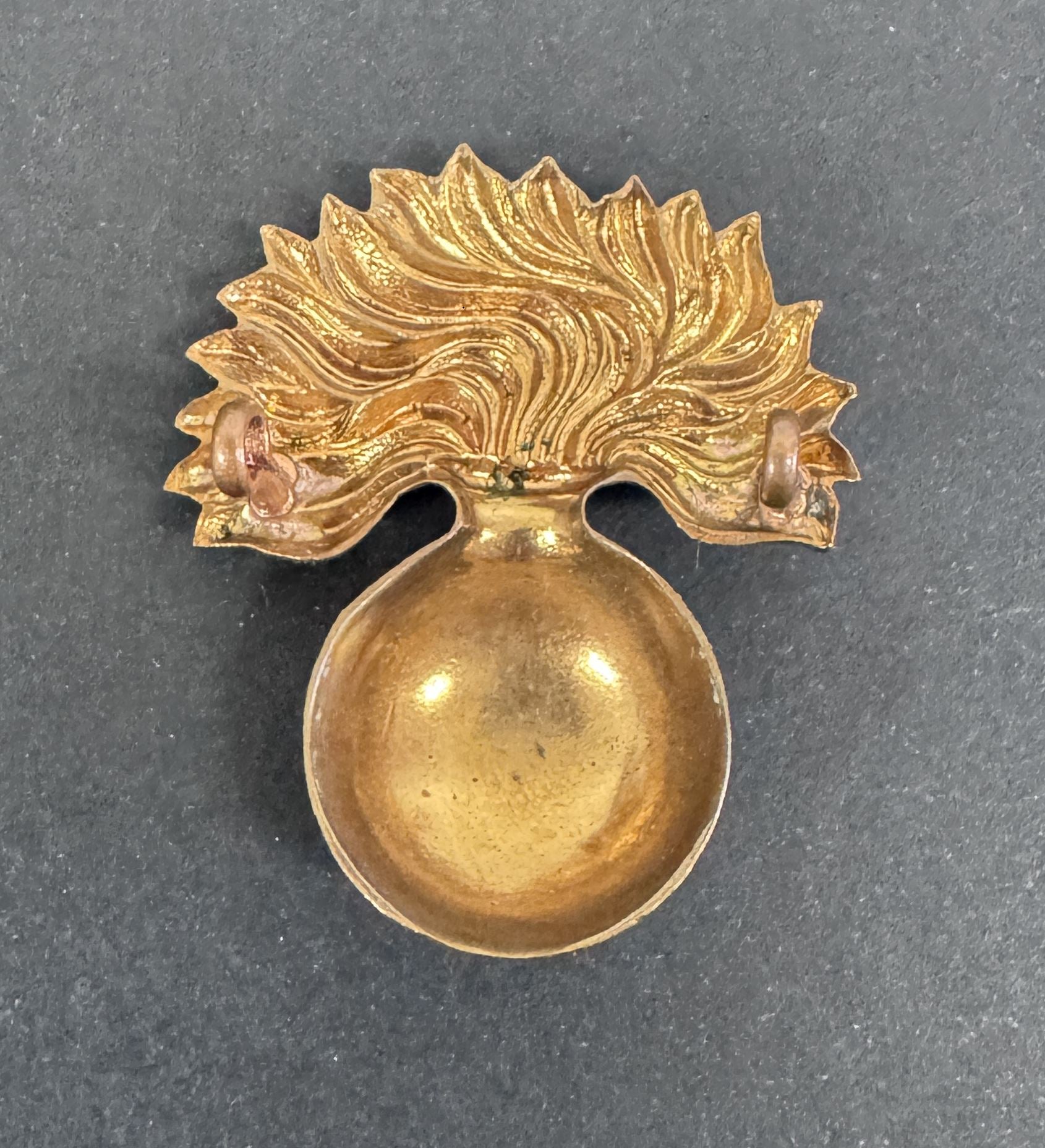 Gold decorative item with a spherical base and leaf-like top on a gray background