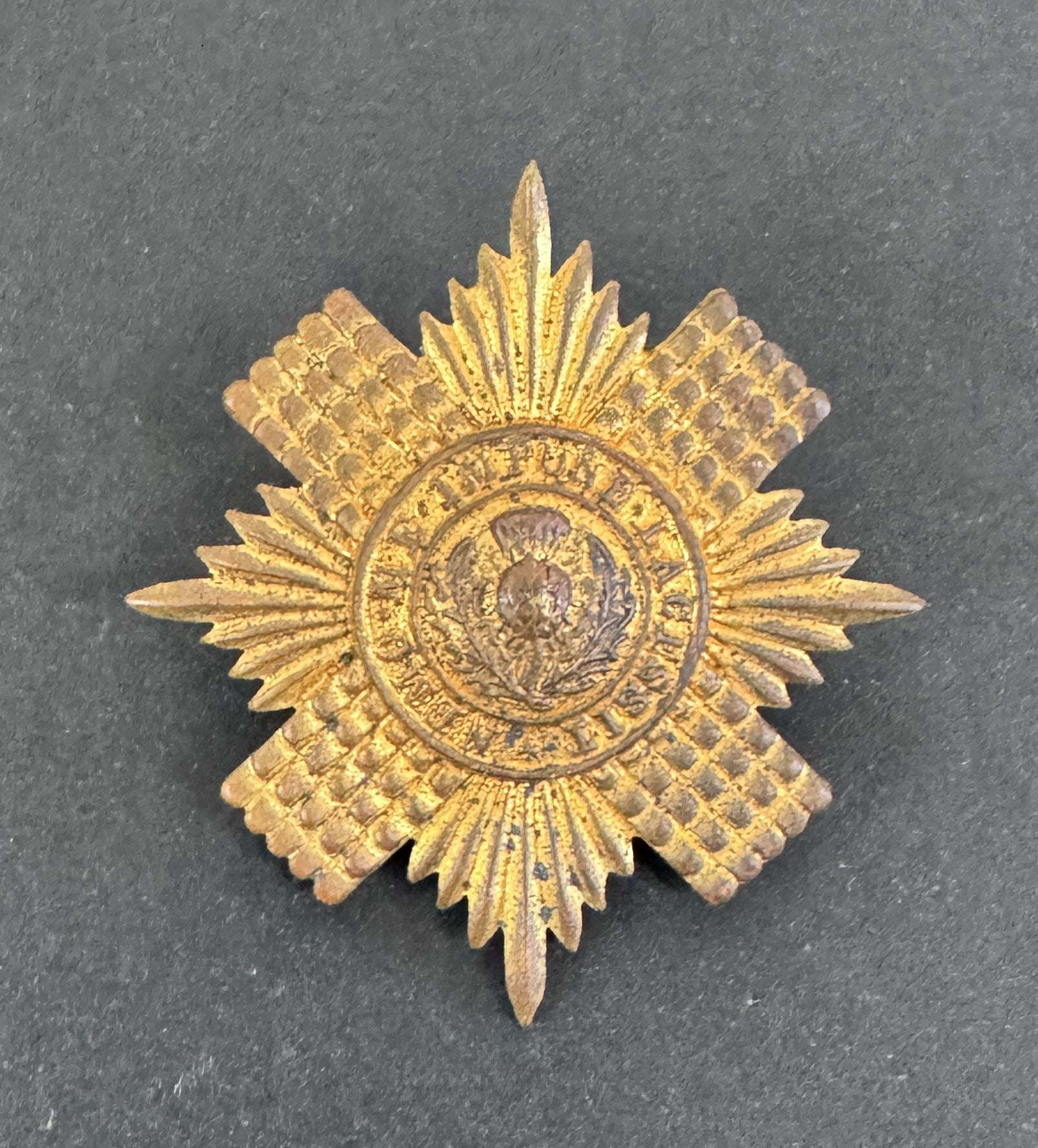 Gold star-shaped military badge on a dark gray background