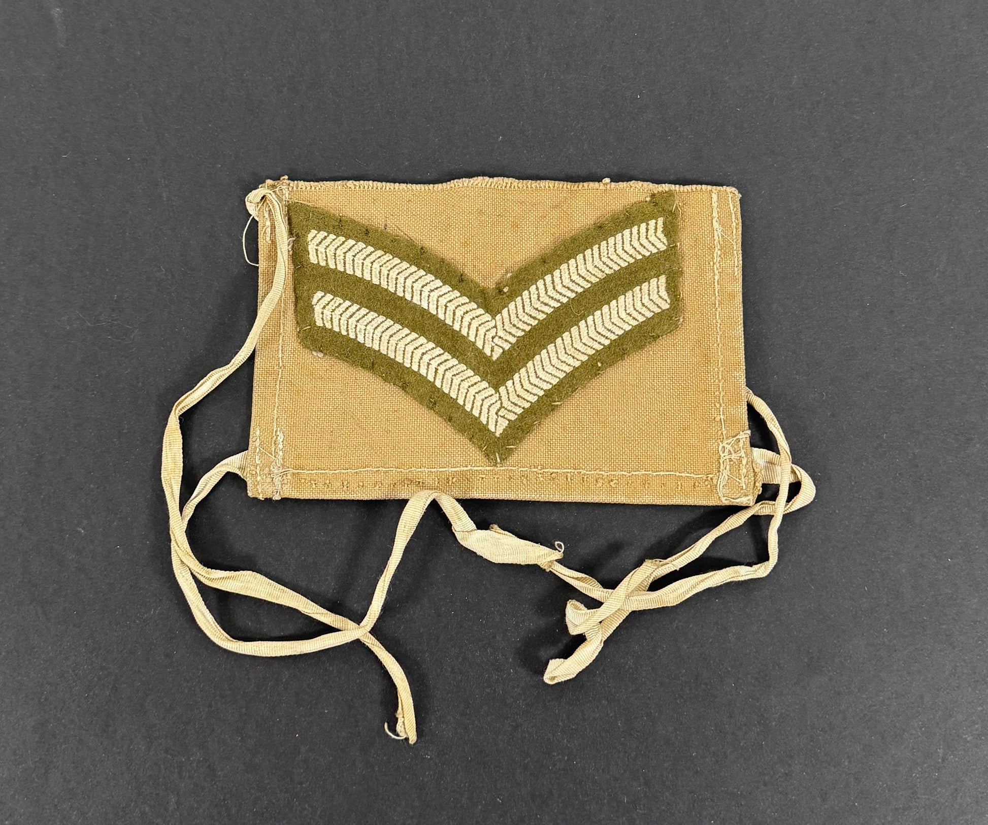Khaki corporal patch with embroidered chevrons on a dark gray background