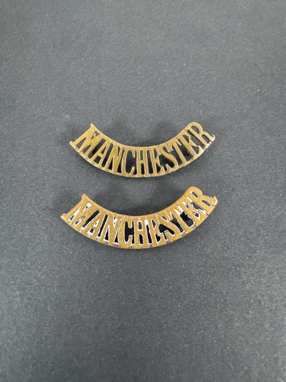 British Army Manchester Regiment Shoulder Title Badges (Pair) – A matching pair of original uniform shoulder titles of the...