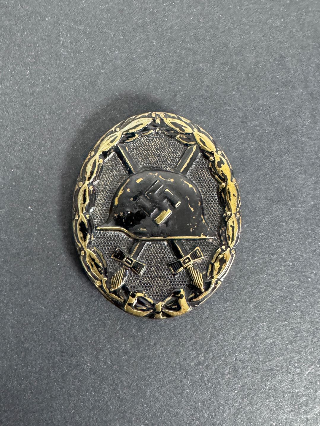 German black wound badge, brass with black painted finish. crossed sword, combat helmet and third Reich symbol.
