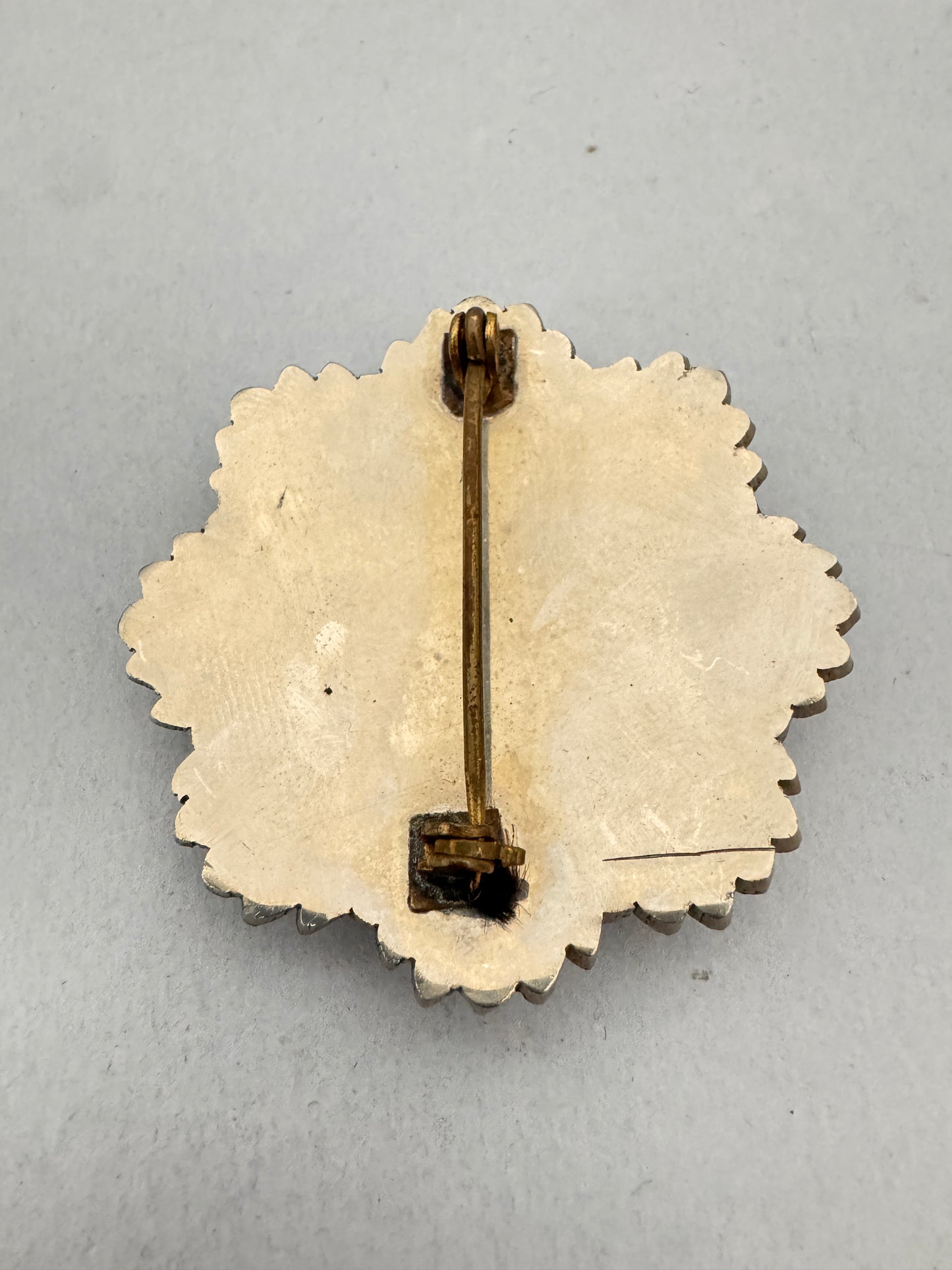 Decorative brooch with scalloped edge on a gray background