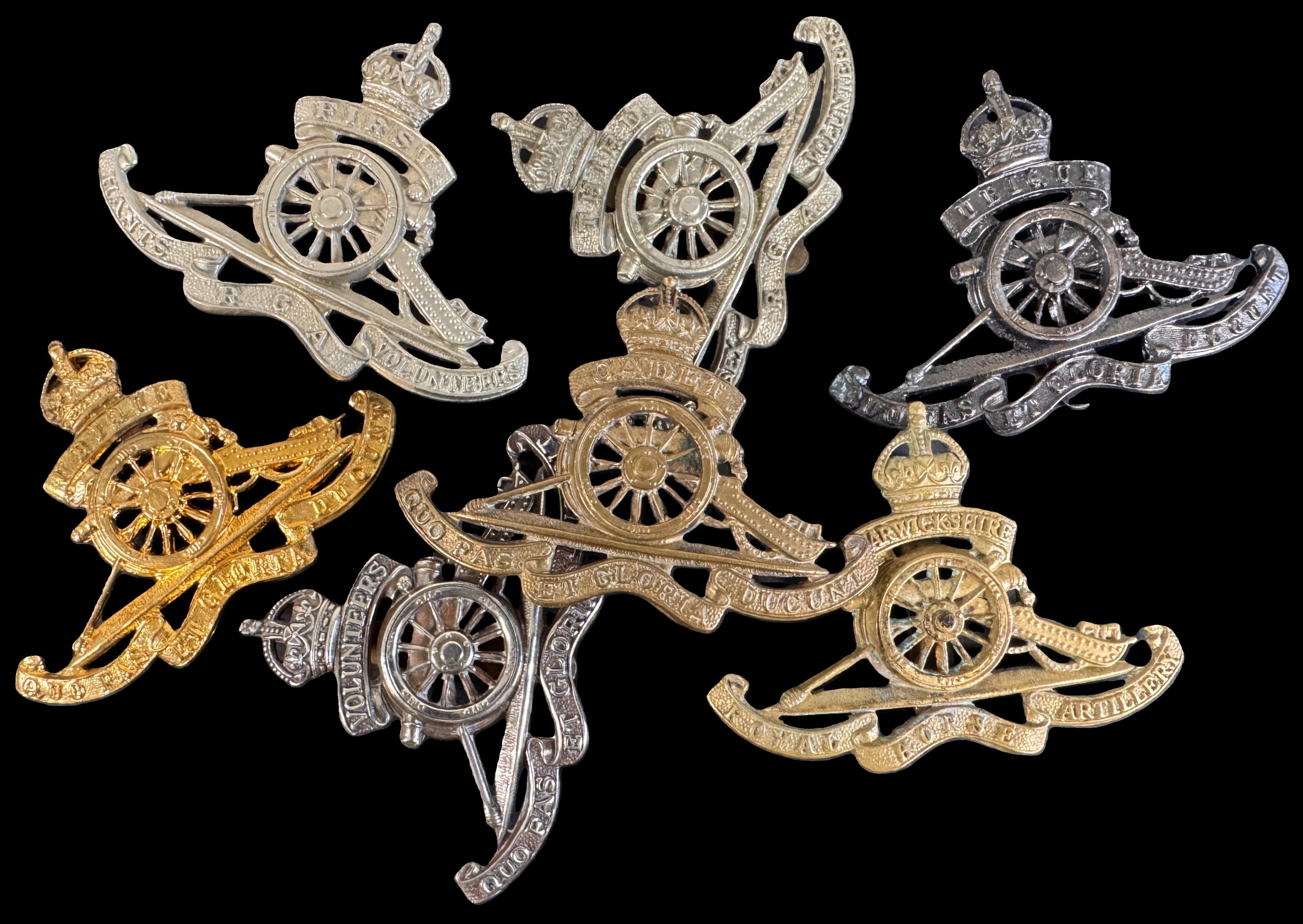 Five military cannon badges in gold, silver, and white gold metals arranged on a solid black background.